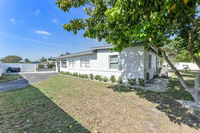 a backyard of a house with large trees and garage