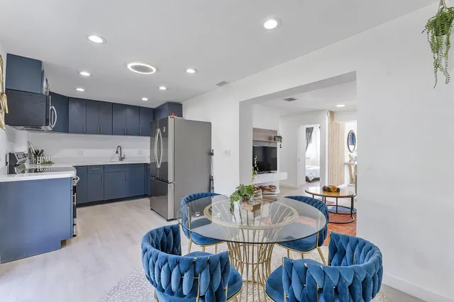 a kitchen with stainless steel appliances kitchen island granite countertop a refrigerator a stove a sink dishwasher with a dining table and chairs