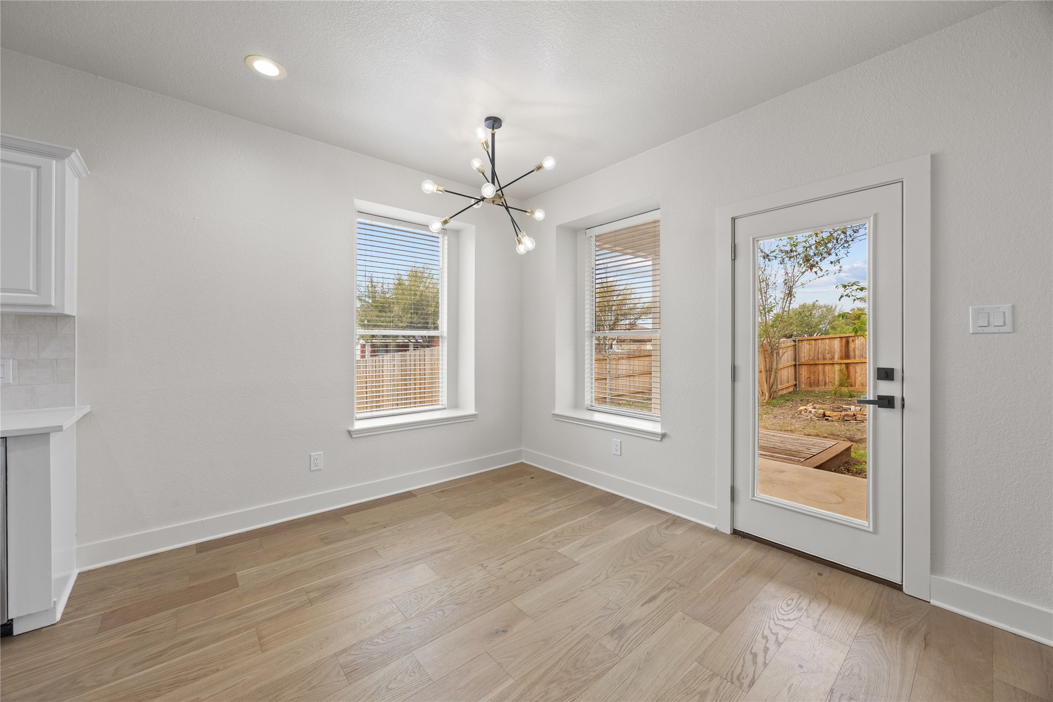 117 Waterloo Drive Kyle, TX 78640 - Photo 5 of 39 an empty room with wooden floor chandelier fan and windows