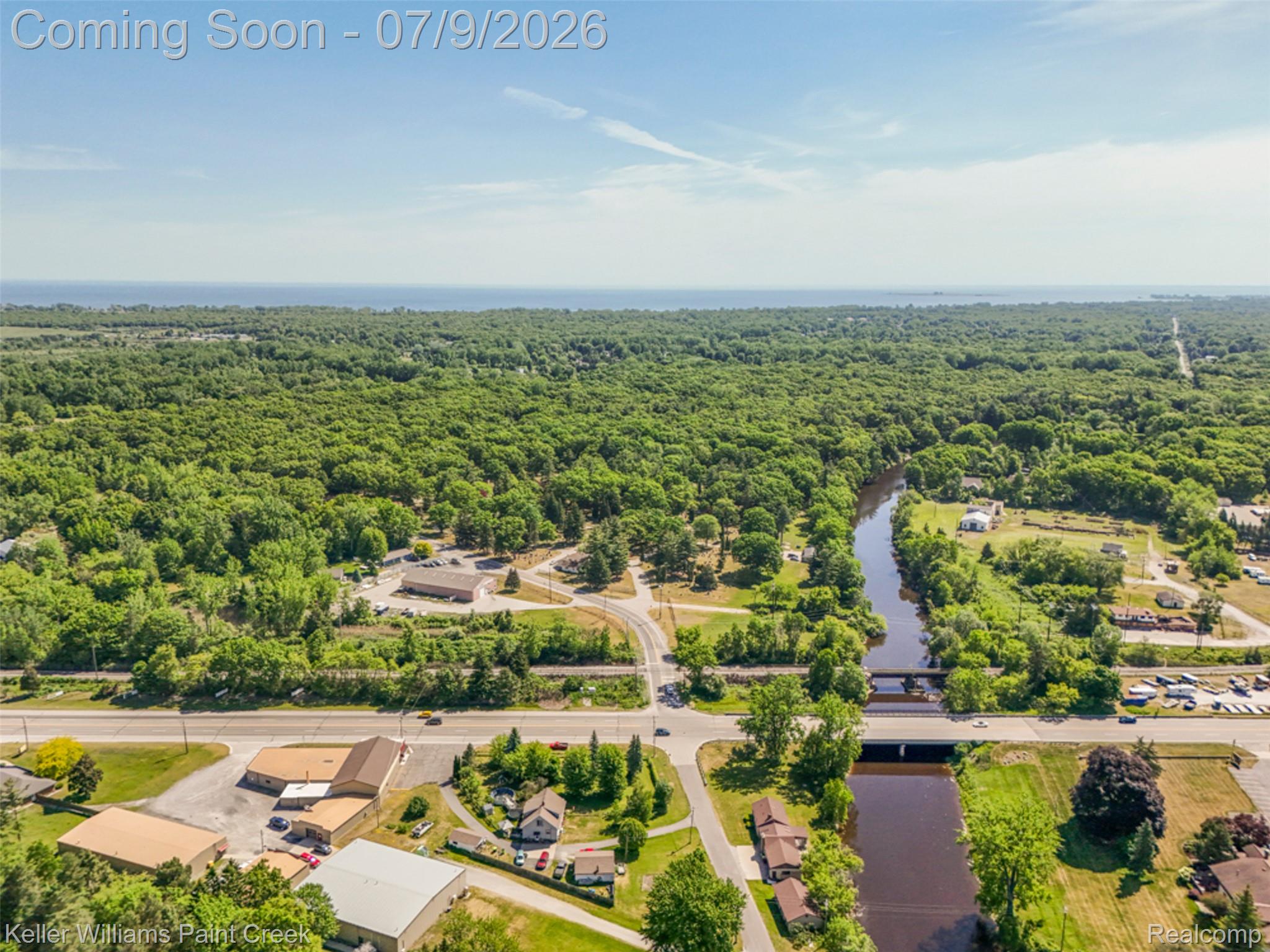 204 Russell Road Kawkawlin, MI 48631 - Photo 62 of 82 Aerial perspective showcasing substantial treed areas, a prominent waterway, and a distant body of water