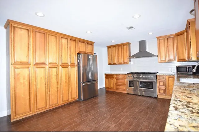 a kitchen with stainless steel appliances granite countertop a refrigerator a stove and a wooden cabinets