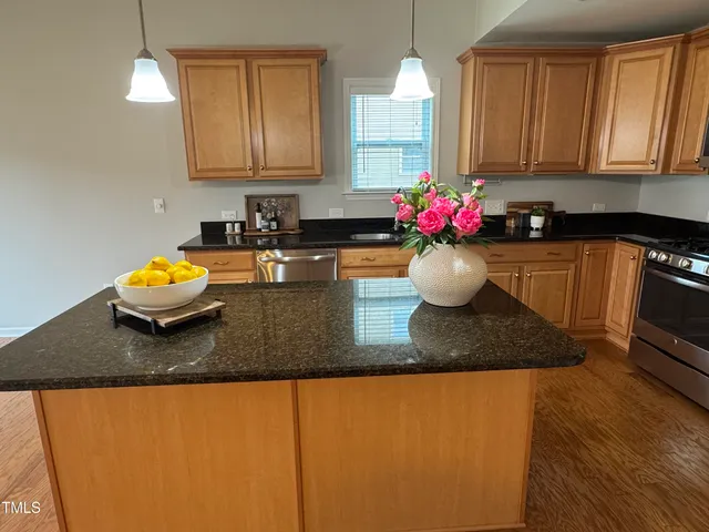 a kitchen with granite countertop a sink a stove and cabinets