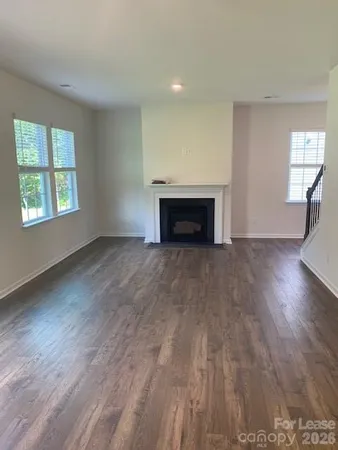 an empty room with wooden floor fireplace and windows