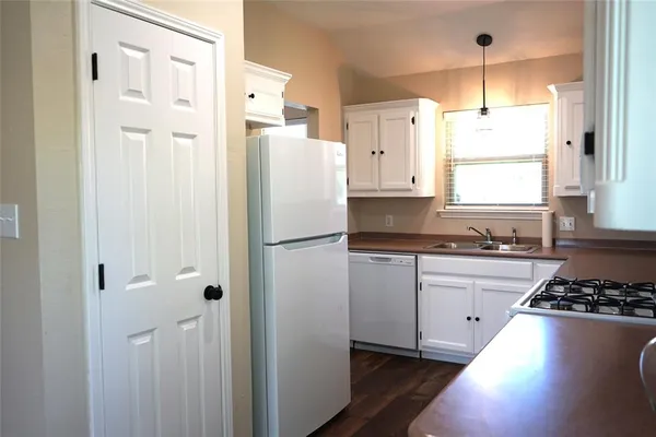 a kitchen with a refrigerator a stove a sink and white cabinets