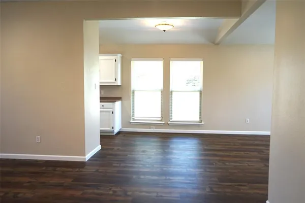 a view of an empty room with window and wooden floor