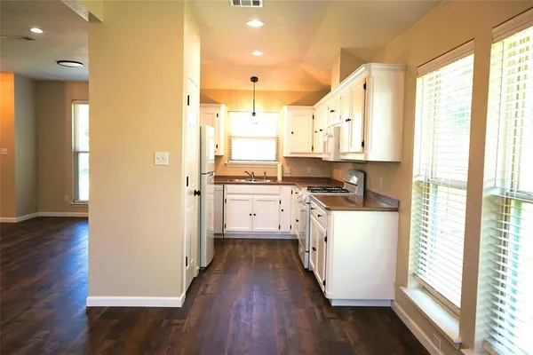 a kitchen with wooden floor and electronic appliances