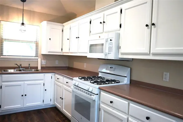 a kitchen with granite countertop white cabinets and white appliances