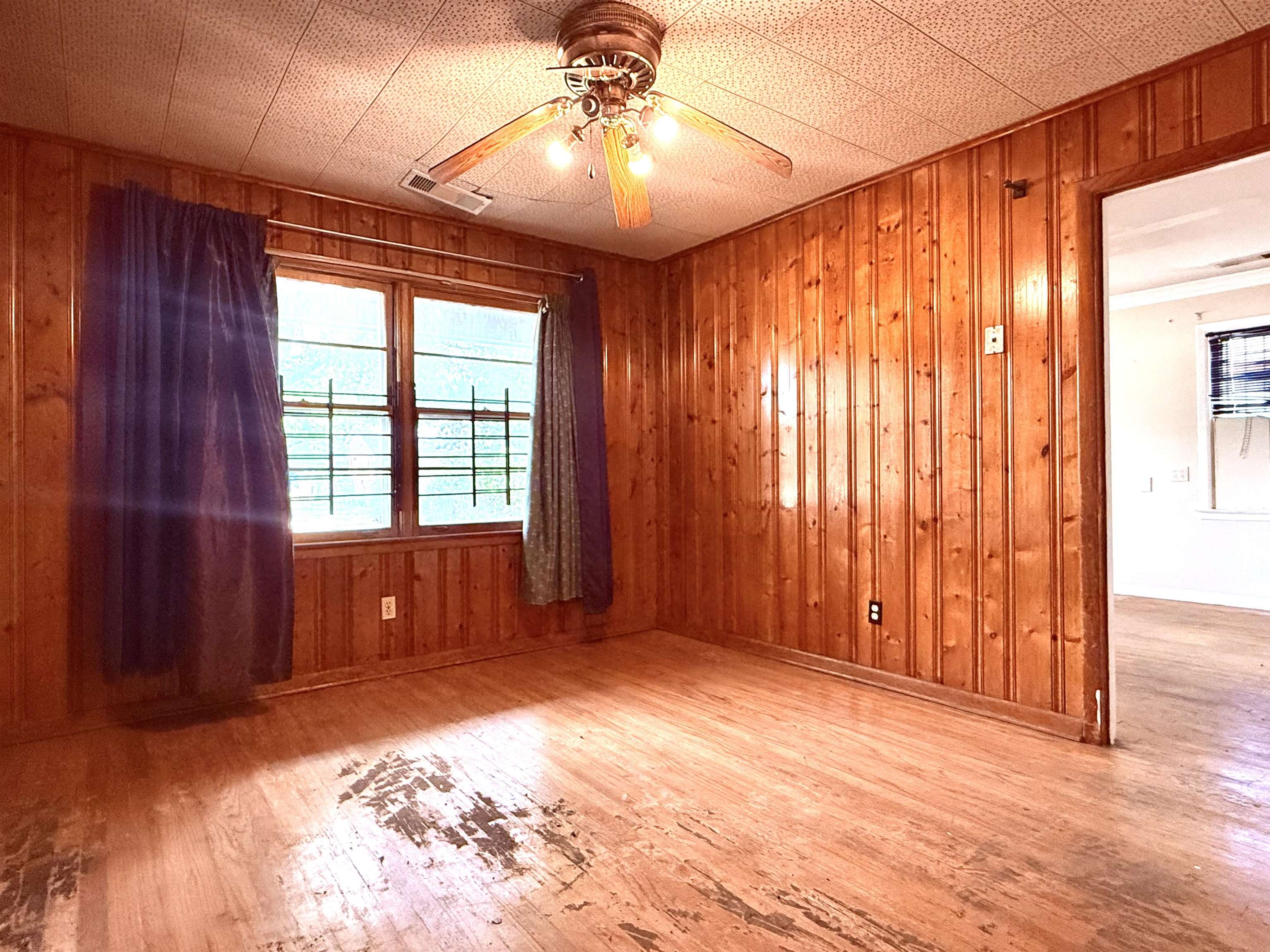 2930 Getwell Road Memphis, TN 38118 - Photo 5 of 25 Room featuring wood paneling on walls, wood-finish flooring, and a ceiling fan with integrated lighting