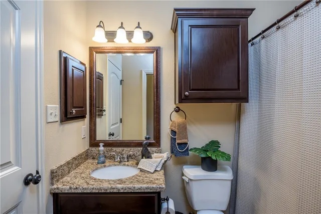 a bathroom with a granite countertop sink and a mirror with toilet
