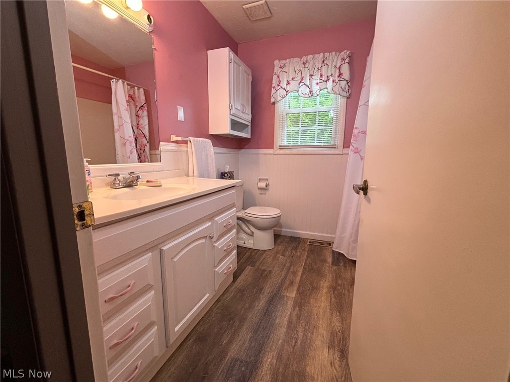57575 Marietta Road Byesville, OH 43723 - Photo 8 of 25 Bathroom featuring a white vanity with integrated sink, wood-finish flooring, a window with blinds, and white beadboard paneling