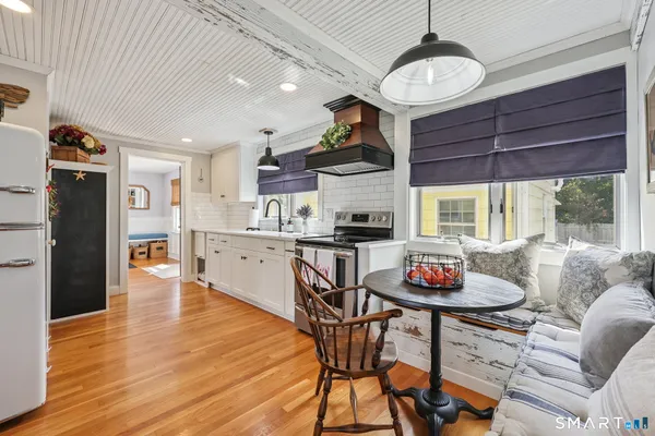 a kitchen with stainless steel appliances granite countertop a stove a refrigerator a dining table and chairs with wooden floor