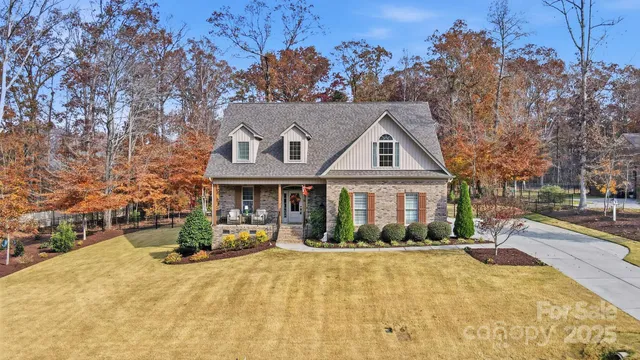 a front view of a house with a yard and a large tree