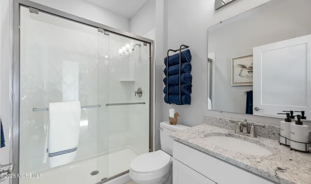 a bathroom with a granite countertop sink mirror vanity and toilet
