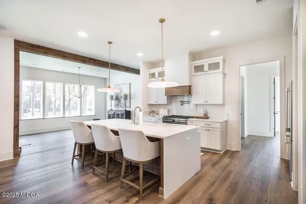 a kitchen with a dining table chairs refrigerator and wooden floor
