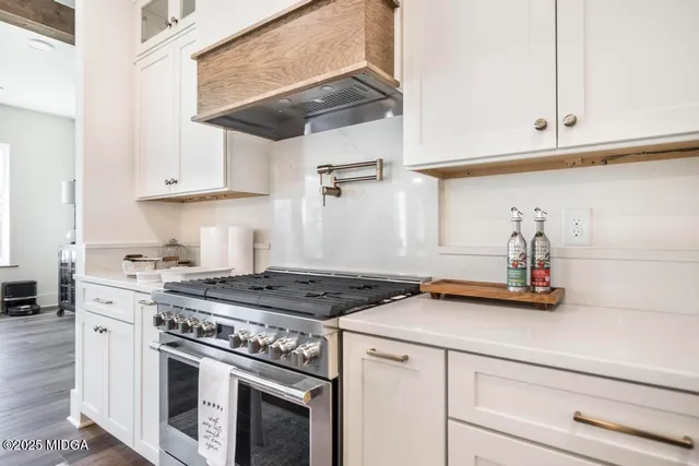 a kitchen with stainless steel appliances granite countertop a stove a sink and white cabinets