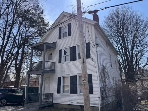 a view of a white house with a large tree