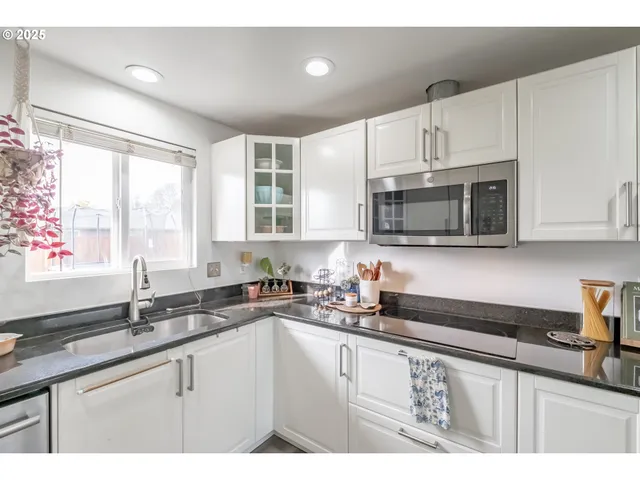 a kitchen with stainless steel appliances a sink a stove a microwave a sink and cabinets