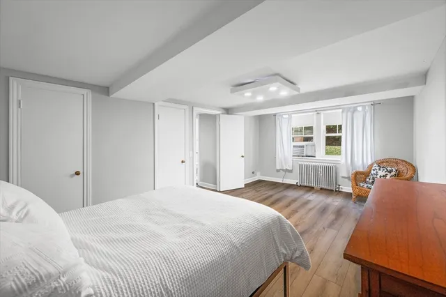 a bedroom with a bed and dresser with wooden floor