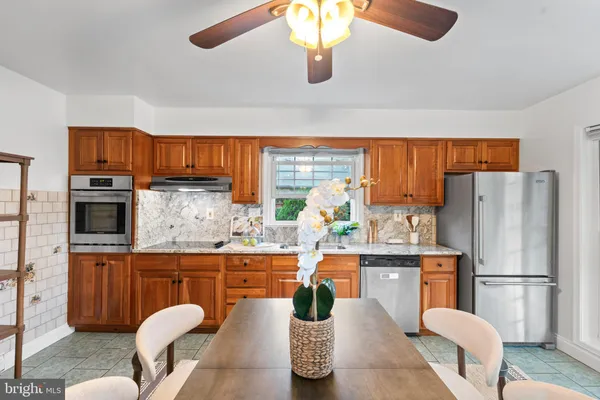 a kitchen with stainless steel appliances granite countertop a refrigerator a stove a sink a dining table and chairs with wooden floor