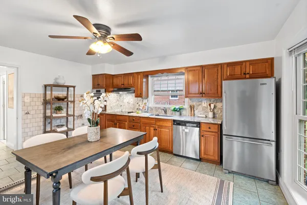 a kitchen with stainless steel appliances granite countertop a dining table chairs refrigerator and cabinets
