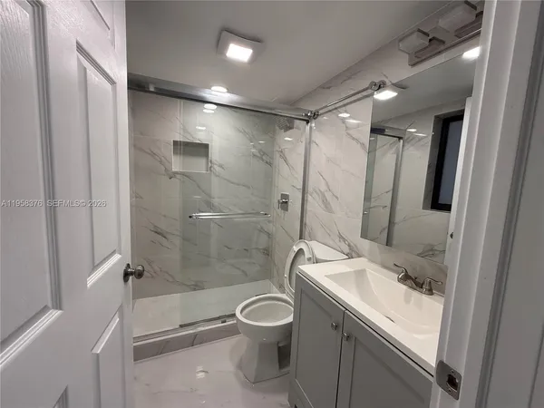 a bathroom with a granite countertop sink toilet and shower