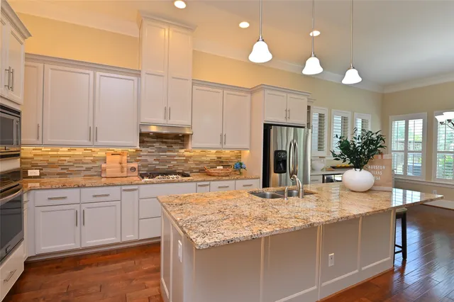 a kitchen with kitchen island granite countertop a stove refrigerator and cabinets