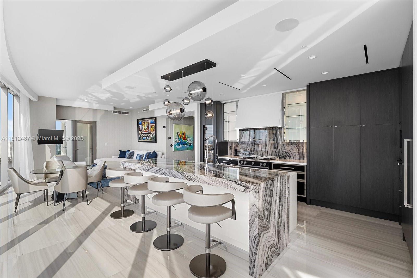 17901 Collins Avenue, Unit 3004 Sunny Isles Beach, FL 33160 - Photo 11 of 61 a large kitchen with stainless steel appliances kitchen island granite countertop a table chairs in it and wooden floors