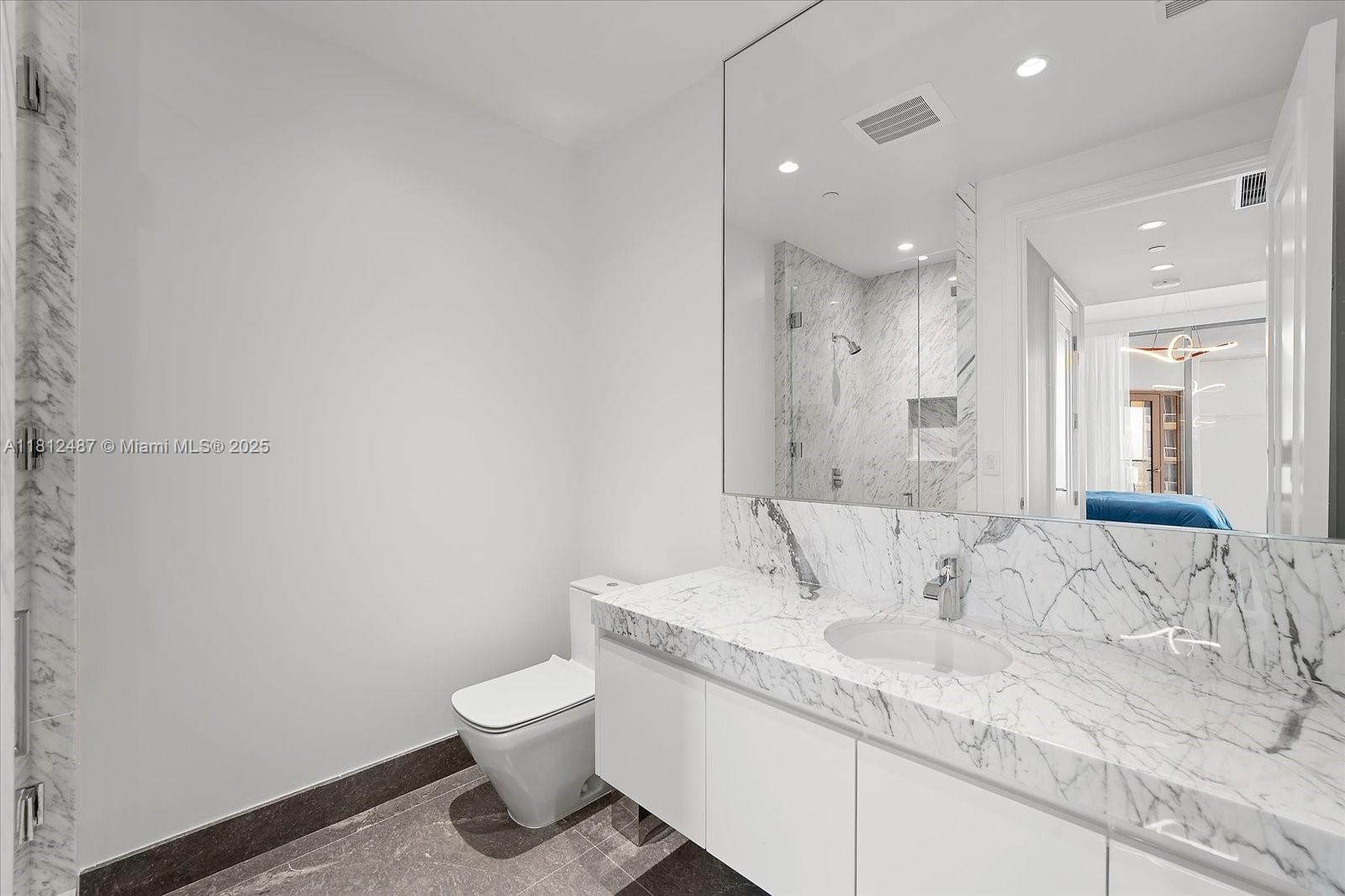 17901 Collins Avenue, Unit 3004 Sunny Isles Beach, FL 33160 - Photo 32 of 61 a bathroom with a granite countertop sink a toilet and a mirror