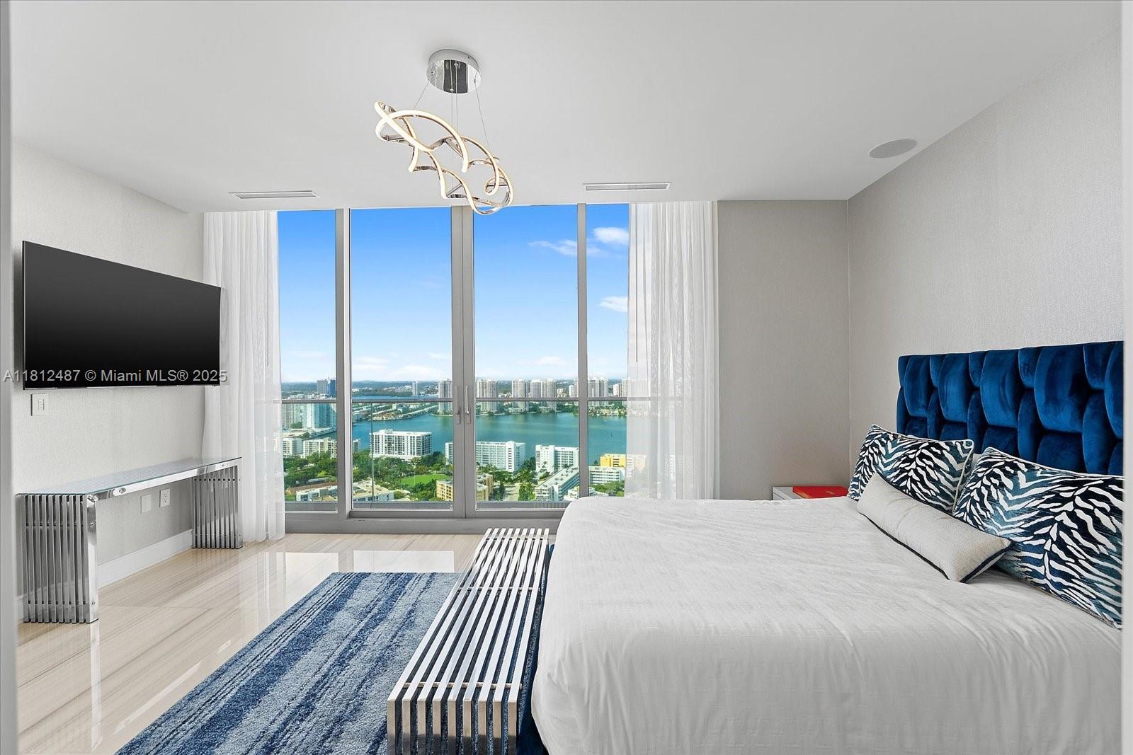 17901 Collins Avenue, Unit 3004 Sunny Isles Beach, FL 33160 - Photo 36 of 61 a bedroom with a large bed and a flat tv screen on dresser