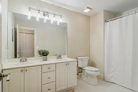 a bathroom with a double vanity sink mirror and toilet