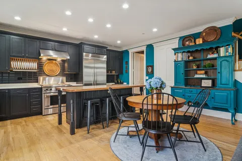 a kitchen with stainless steel appliances kitchen island granite countertop a stove a sink and a dining table