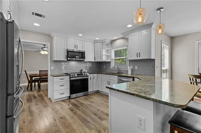 a kitchen with kitchen island granite countertop a sink counter top space appliances and cabinets