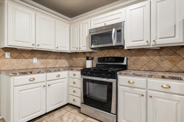 a kitchen with white cabinets and stainless steel appliances