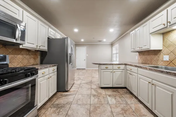 a kitchen with stainless steel appliances granite countertop a stove a sink and a microwave