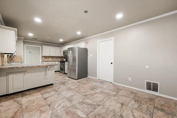 a large kitchen with stainless steel appliances kitchen island granite countertop a refrigerator and a stove top oven
