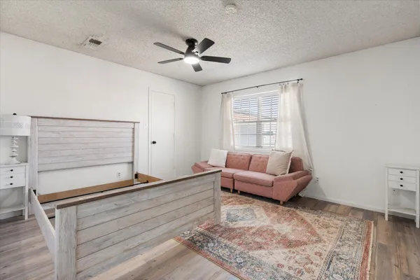 a bed sitting in a bedroom next to a window and a chair