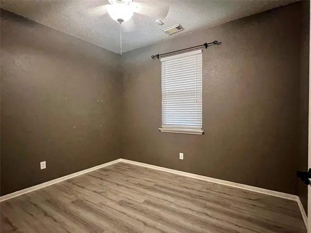 an empty room with a window and wooden floor