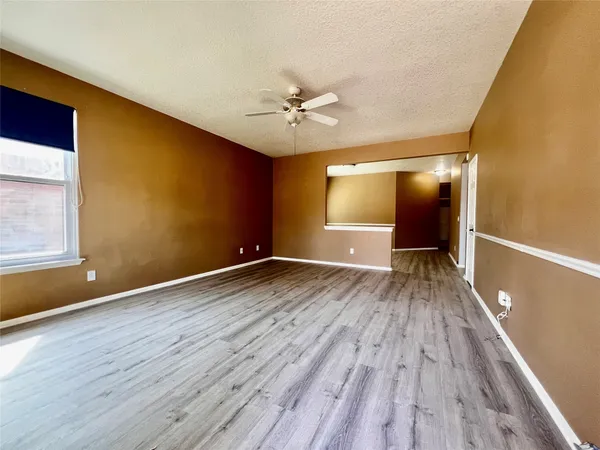 a view of an empty room with window and wooden floor