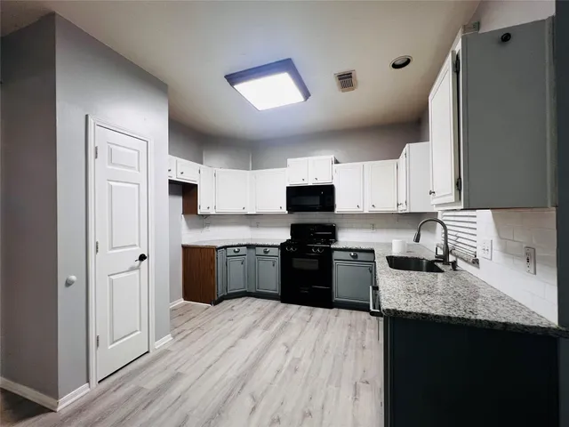 a kitchen with granite countertop a refrigerator stove top oven and sink