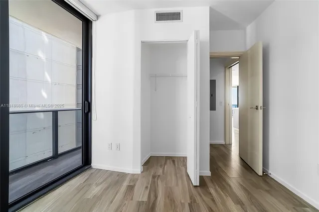 a view of a hallway with wooden floor and a bathroom