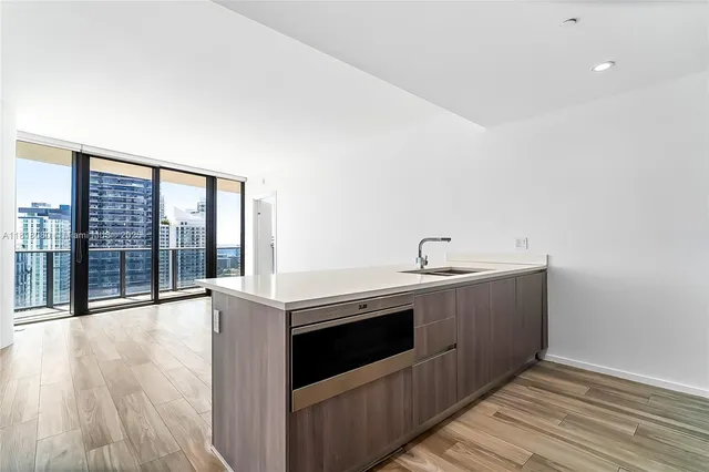 a view of a kitchen with stainless steel appliances wooden floor and a large window