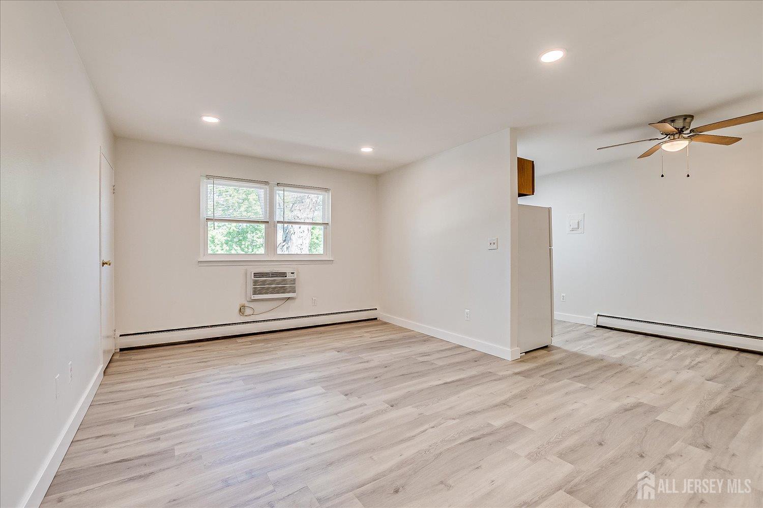 289 Main Street, Unit 4P Spotswood, NJ 08884 - Photo 5 of 22 an empty room with wooden floor and windows