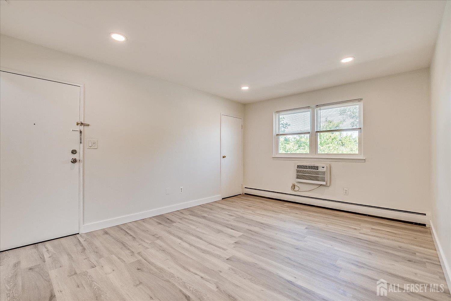 289 Main Street, Unit 4P Spotswood, NJ 08884 - Photo 6 of 22 an empty room with wooden floor and windows
