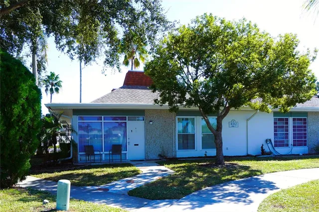 a front view of a house with a yard and large tree
