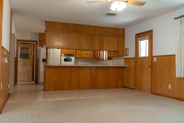 a view of an empty room with chandelier fan and a window