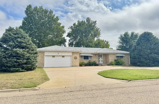 a view of a white house with a big yard and large trees