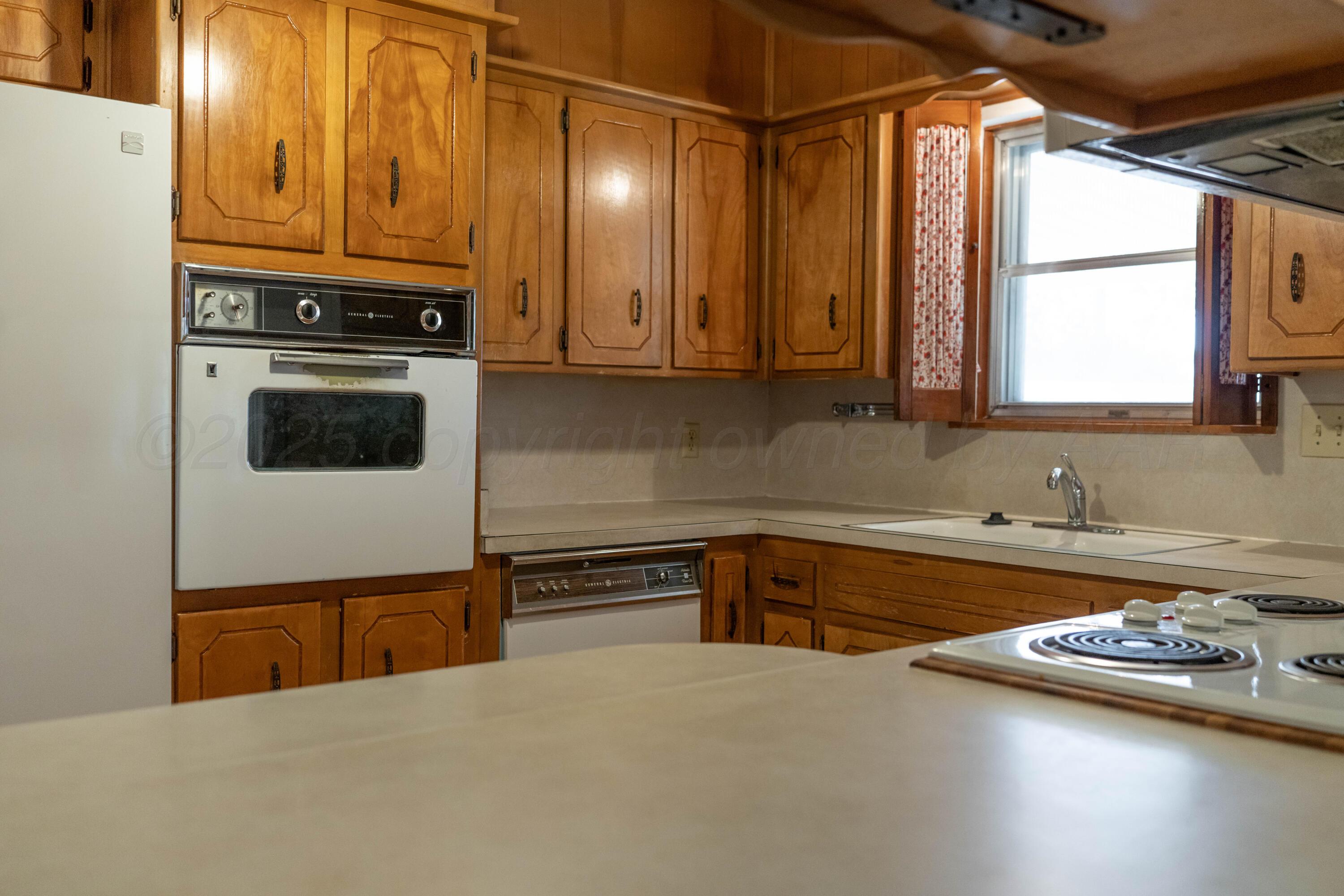 1315 South Canadian Street Wheeler, TX 79096 - Photo 22 of 44 a kitchen with a sink a stove and cabinets