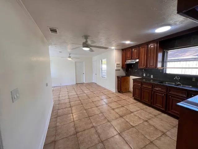 a large kitchen with kitchen island granite countertop a sink cabinets and stainless steel appliances