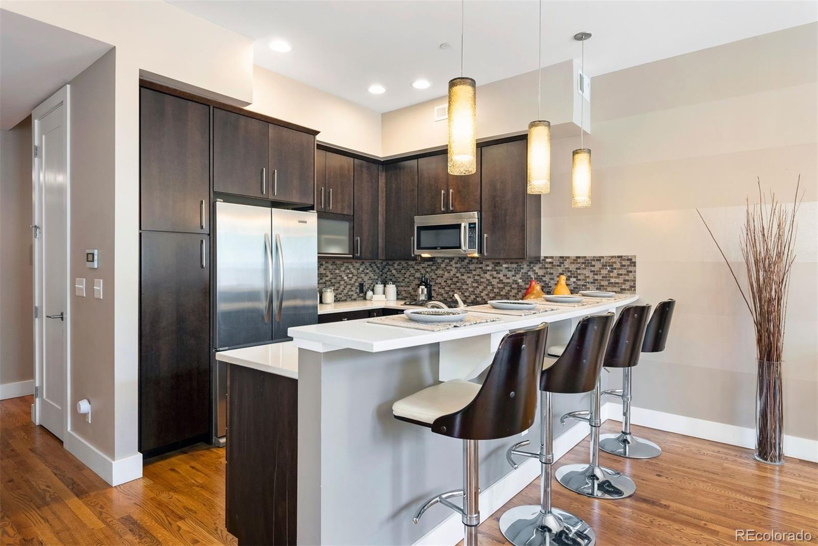 340 South Lafayette Street, Unit 102 Denver, CO 80209 - Photo 14 of 35 a kitchen with kitchen island granite countertop a sink and refrigerator