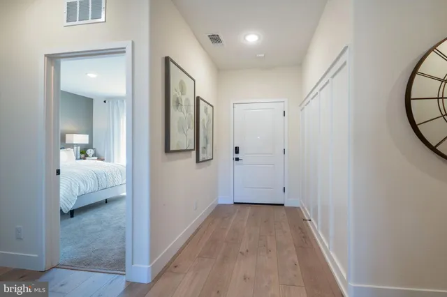a view of a hallway with wooden floor and bathroom